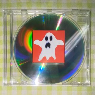 Fotografia d'una funda de CD amb un CD dins i una enganxida amb el dibuix d'un fantasma que cobreix parcialment el CD.